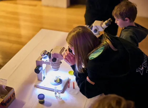 Young visitors examining specimens through microscopes at Beaker Street Festival, Tasmanian Museum and Art Gallery, Hobart