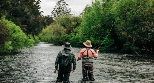 Two anglers fly fishing in St Patricks River with one casting a line, near Launceston, Tasmania