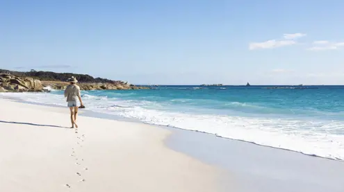 A walker on the white sand beach at Cosy Corner, larapuna / Bay of Fires Conservation Area, Tasmania