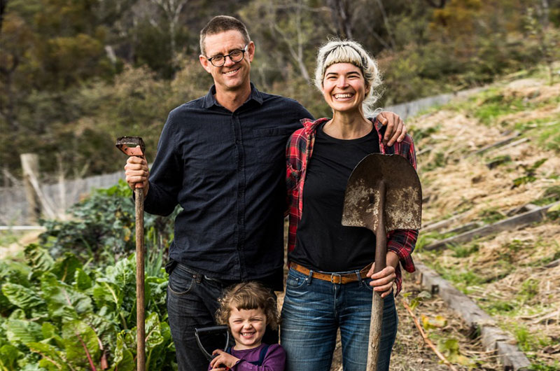 A young family stand in their vegetable garden 