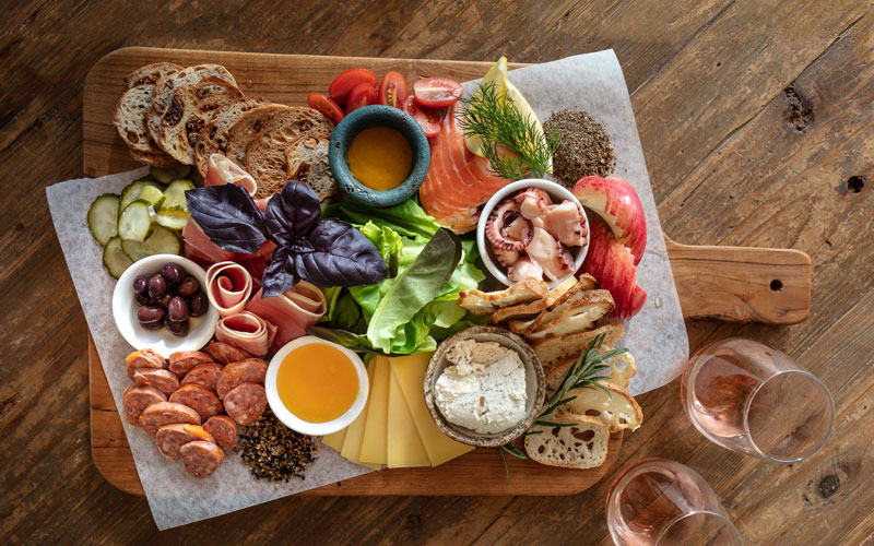 Tasmanian gourmet produce displayed a wooden board with two glasses of wine 